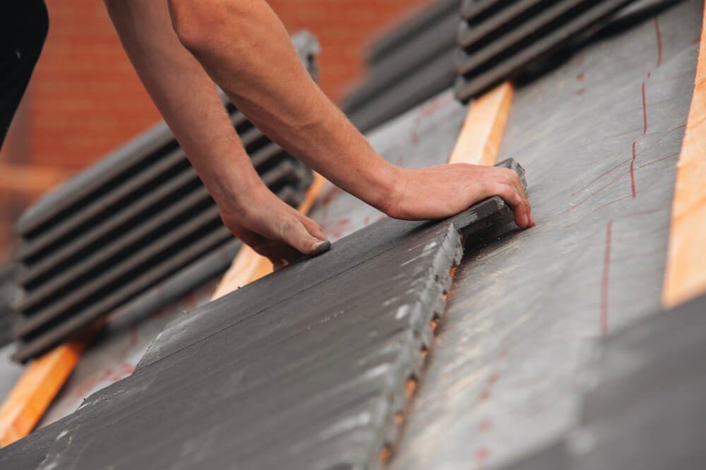 roofing contractor applying material on a sloped roof