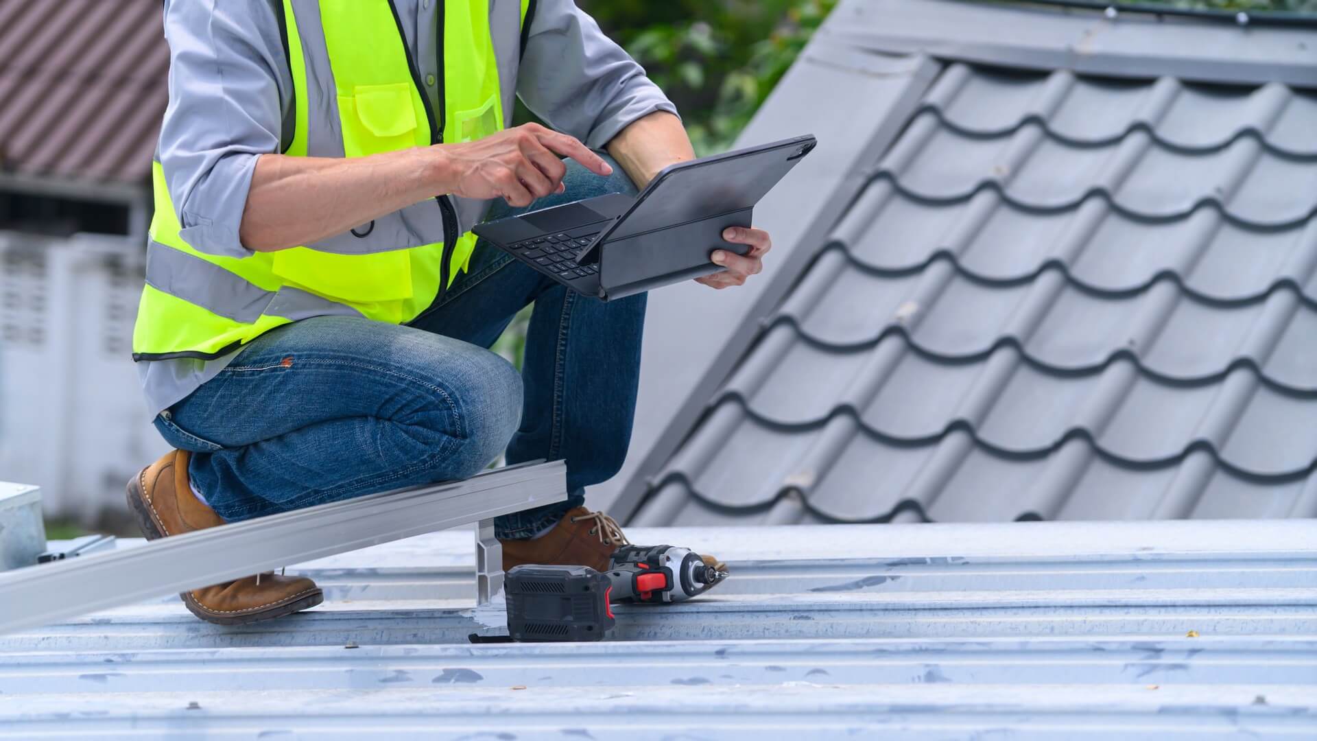 roofing contractor using a tablet on a metal roof